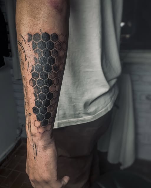 Tatuaje blackwork de panal de abejas geométrico en el antebrazo